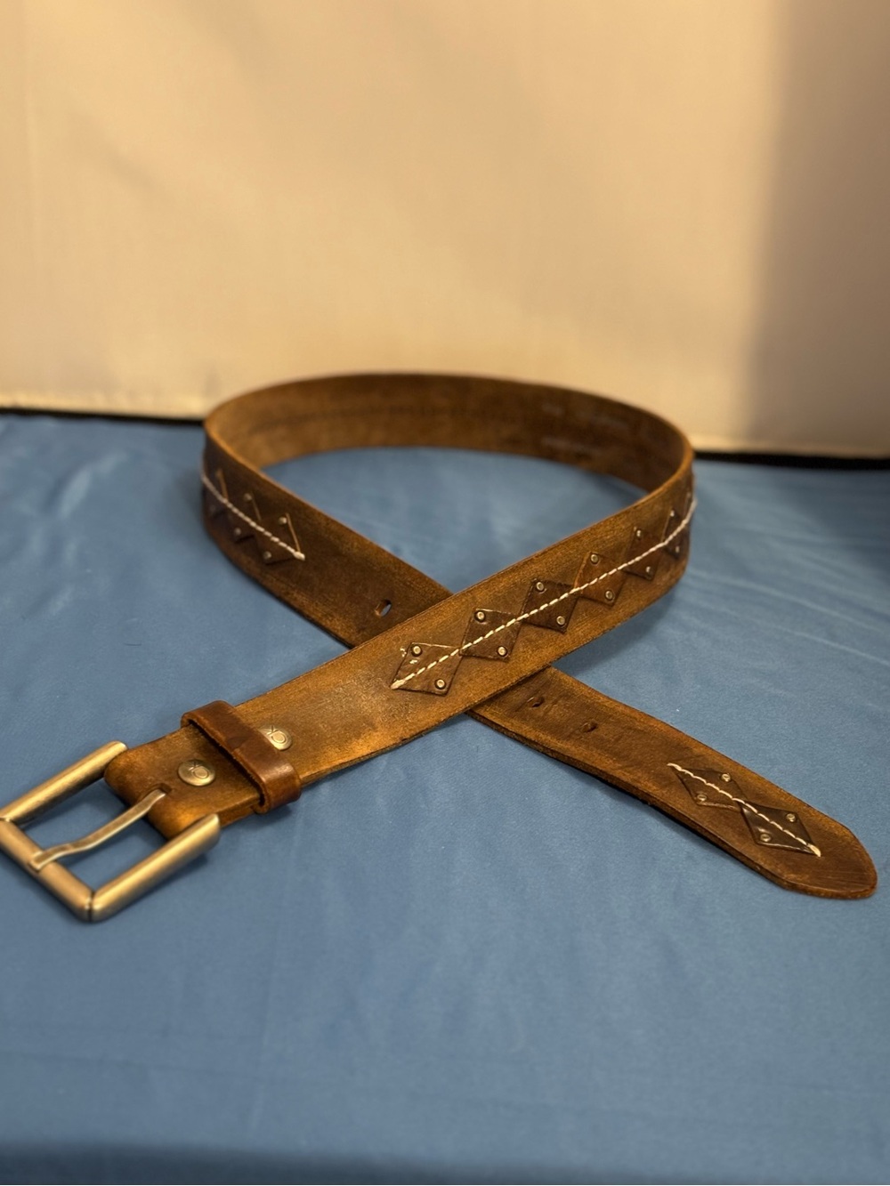 Brown distressed leather belt with stitced diamond pattern with the letters CK